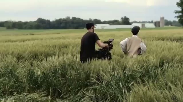 operator in the wheat field filming a period actor walking away