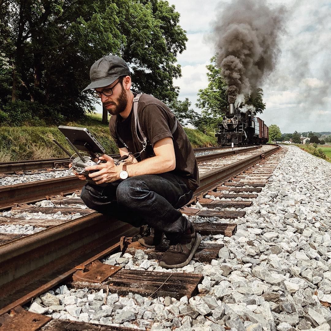 Adam flying the drone from the tracks as the steam locomotive approaches, photo by @seemurray