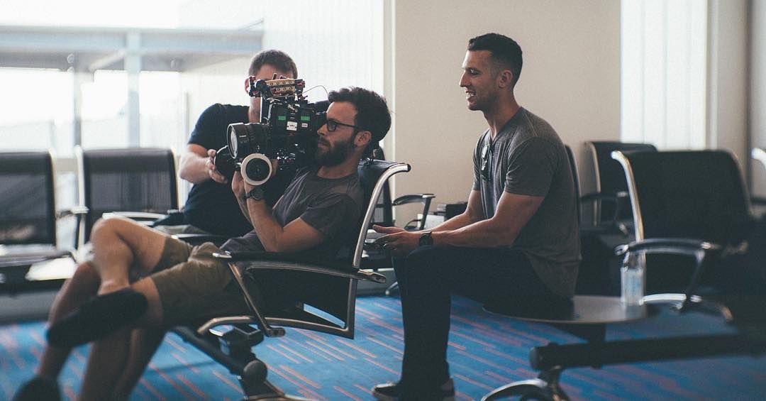 Adam operating from a reclined airport gate chair, crew around him
